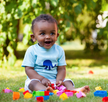 Baby playing in grass with blocks